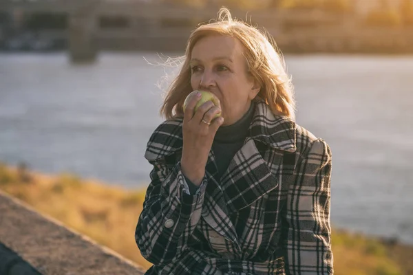 Senior Vrouw Geniet Van Eten Apple Zittend Door Rivier Getinte — Stockfoto