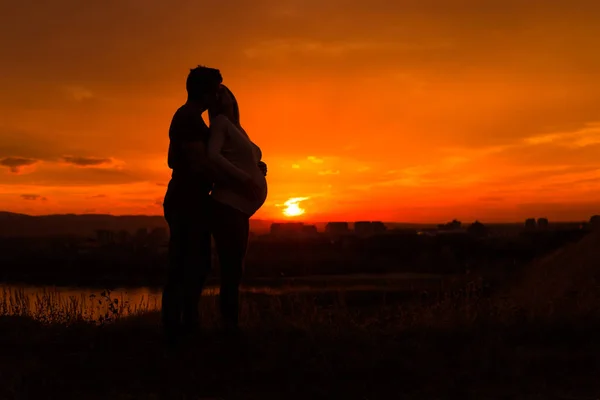 夫と妊娠中の妻と一緒に過ごす時間を楽しみながらのキスのシルエット屋外 トーンのイメージ — ストック写真