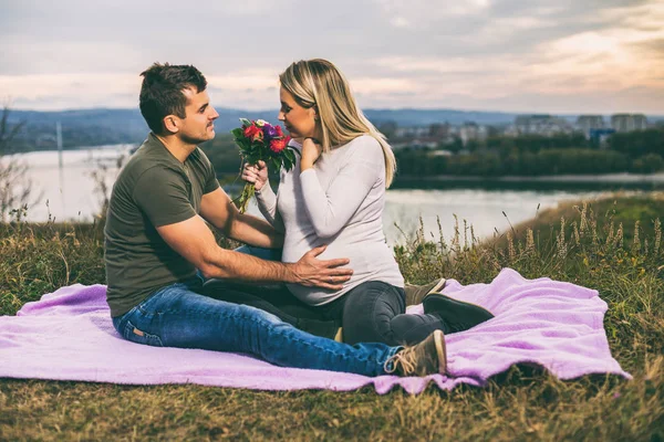 夫しながら妊娠中の妻を与える花を一緒に時間を過ごすお楽しみください屋外 トーンのイメージ — ストック写真