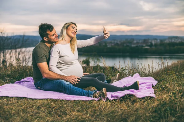 幸せな夫と妊娠中の妻と一緒に過ごす時間を楽しみながら Selfie を取って屋外 トーンのイメージ — ストック写真