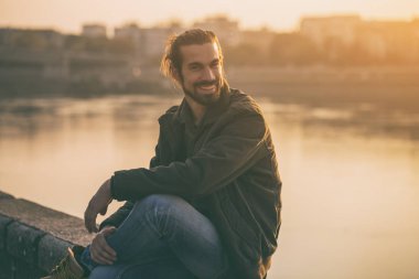 Yakışıklı modern işadamı nehir kıyısında dinlenme sahiptir. Tonlu görüntü.