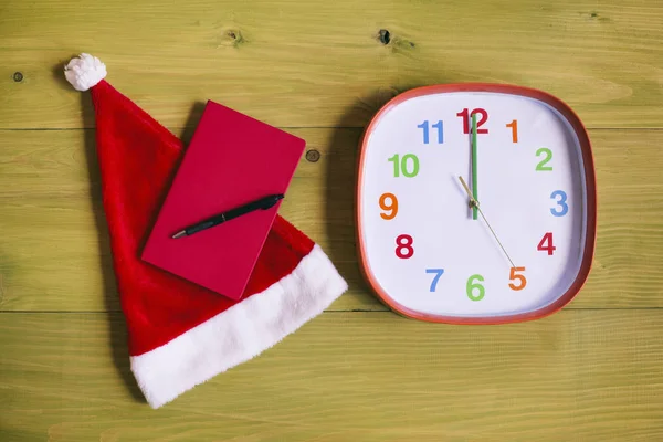 サンタ帽子 個人的なオルガナイザー 時計表示深夜木製テーブルのイメージです トーンのイメージ — ストック写真