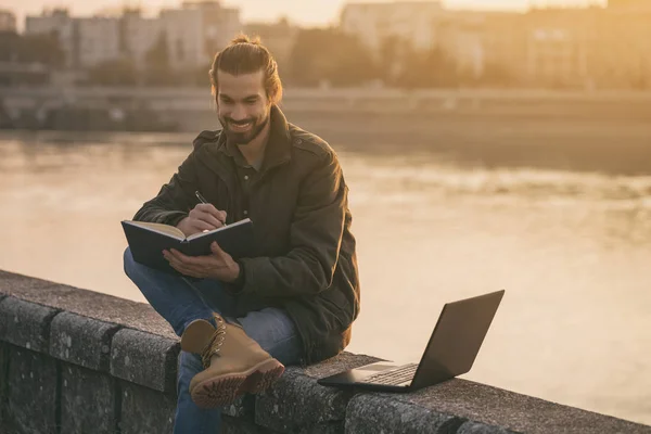 Schöner Geschäftsmann Mit Persönlichem Organisator Und Laptop Während Fluss Sitzt — Stockfoto