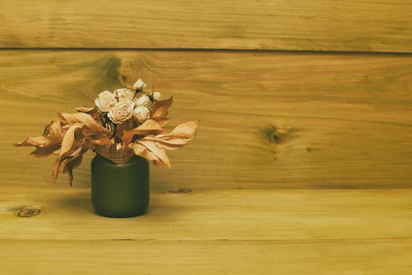 Vase with dried flowers on wooden table.Toned photo.