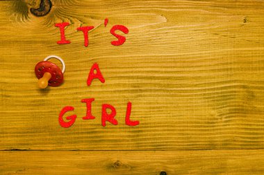 Metin, ahşap masada emzik olan bir kız. Tonlu fotoğraf.