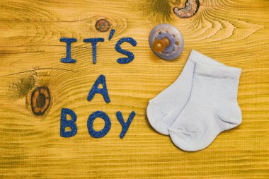 Metin, ahşap masada emzik ve küçük bebek çoraplı bir çocuk. Tonlu fotoğraf.