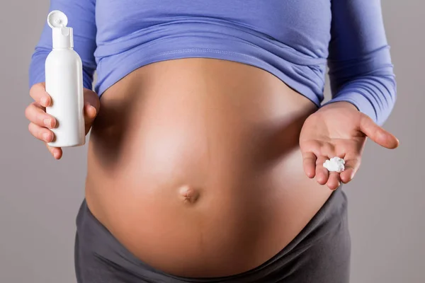 孕妇在灰色背景上腹部涂抹保湿剂的图像 — 图库照片