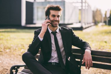 Şık işadamı dışarıda otururken telefon kullanıyor. Tonlu görüntü.