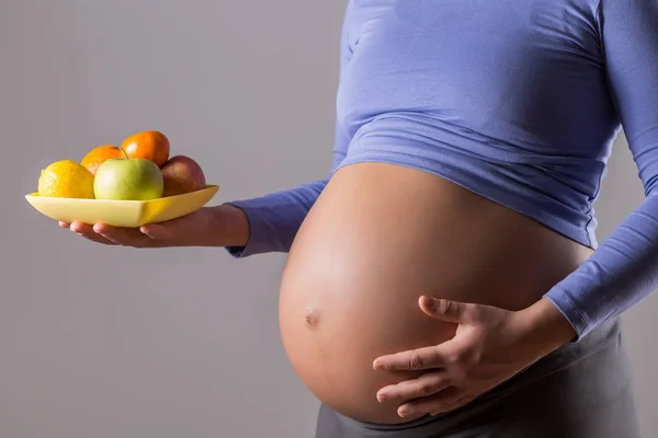 Image Close Stomach Pregnant Woman Holding Fruit Gray Background — Stock Photo, Image