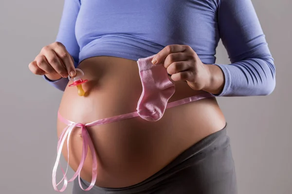 Imagen Estómago Mujer Embarazada Con Una Cinta Rosa Sosteniendo Calcetines — Foto de Stock