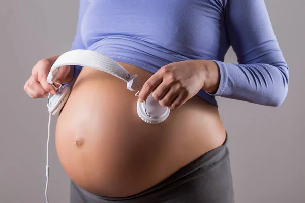 Imagem Fechar Estômago Mulher Grávida Segurando Fones Ouvido Fundo Cinza — Fotografia de Stock