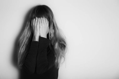 Depresif kadın duvarın önünde tek başına duruyor. Kasıtlı olarak siyah beyaz görüntü.