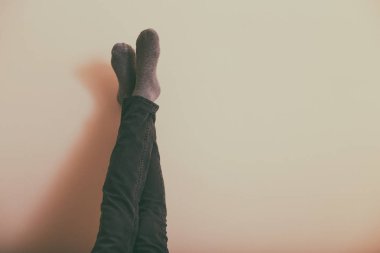 Bacakları duvarın önünde dinlenen bir kadın. Tonlu bir fotoğraf..