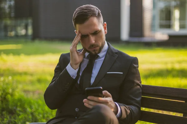 Orolig Affärsman Som Använder Telefon Medan Sitter Utomhus Tonad Bild — Stockfoto