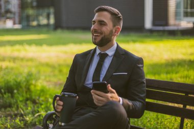 Zarif işadamı telefon kullanarak ve açık kahve içme. Tonlu fotoğraf.