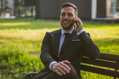 Şık işadamı dışarıda otururken telefon kullanıyor. Tonlu görüntü.