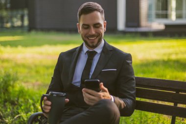 Zarif işadamı telefon kullanarak ve açık kahve içme. Tonlu fotoğraf.