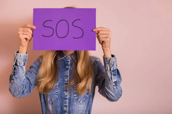 Mulher Segurando Papel Com Palavra Sos Frente Parede — Fotografia de Stock