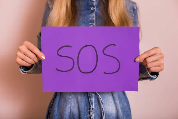 Mujer Sosteniendo Papel Con Palabra Sos Pie Delante Pared —  Fotos de Stock