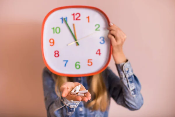 Frau Hält Kaputte Zigaretten Und Uhr Vor Der Wand — Stockfoto