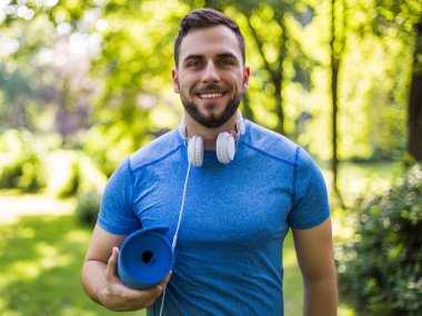 Portrait of handsome sporty man standing in the park.