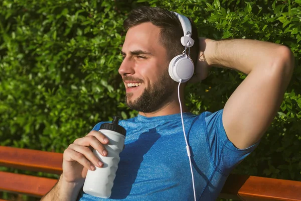 Schöner Mann Mit Kopfhörern Trinkt Wasser Und Ruht Sich Nach — Stockfoto