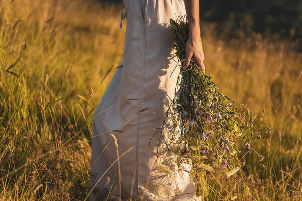 Woman walking with bouquet of flowers and enjoys in the beautiful nature.