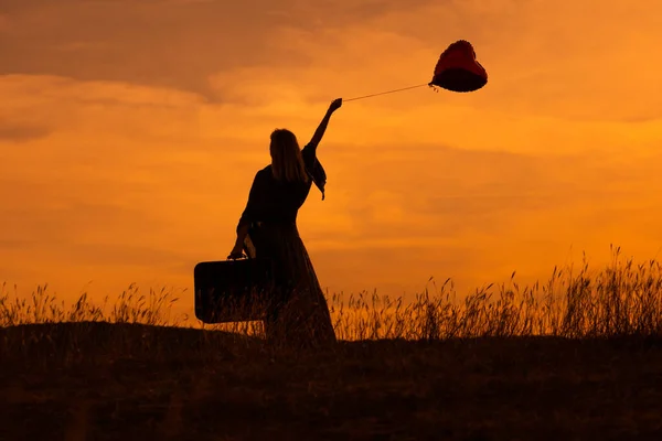 Silueta Una Mujer Sosteniendo Una Maleta Globo Forma Corazón Mientras —  Fotos de Stock