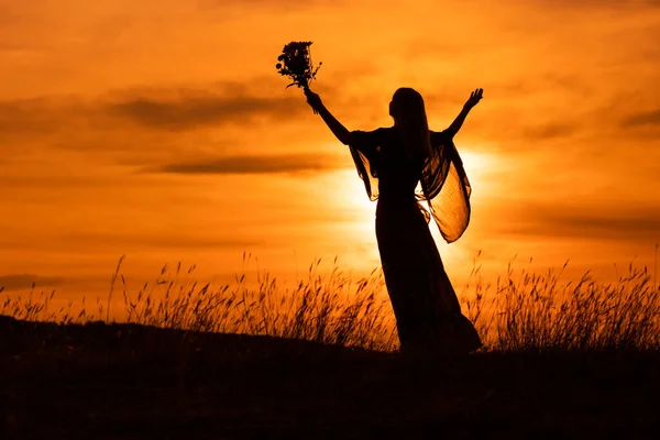 Silhueta Uma Mulher Com Braços Estendidos Segurando Flores Olhando Para — Fotografia de Stock