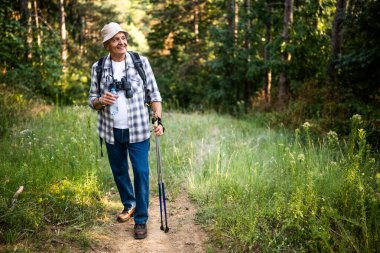 Kaygısız son sınıf öğrencisi su içerken sırt çantasıyla yürüyüş yapmak ve doğada sırık gezdirmekten zevk alıyor..