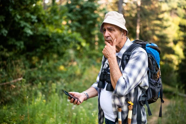 Kıdemli yürüyüşçünün kaybolmasından endişeleniyor ve doğa yürüyüşü yaparken doğru yönü bulmak için akıllı telefonu kullanıyor..