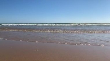 Sahilde koşan bir insanın ayaklarına yakın çekim. Su sıçratıyor.