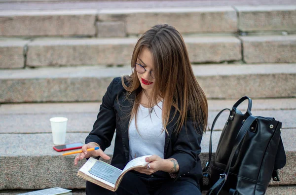 Mujer de negocios trabajando en la calle. Se sienta en los escalones con un café portátil y bloc de notas . — Foto de Stock