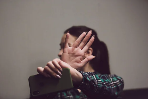 Flickan vägrar att fotografera. Hon håller en telefon i händerna och stänger händerna på kameran. — Stockfoto