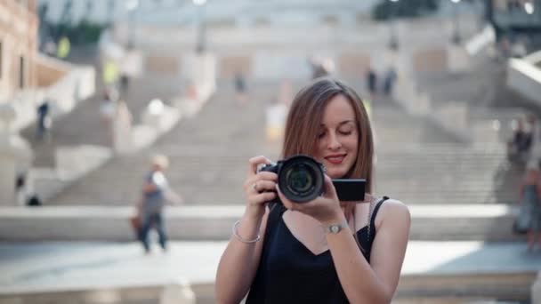 Attraente fotografa femminile sorridente che tiene la sua macchina fotografica digitale nera e scatta incredibili foto di riferimento. Ragazza creativa in cerca di migliore composizione fotografica, la registrazione di ricordi della città sulla macchina fotografica — Video Stock