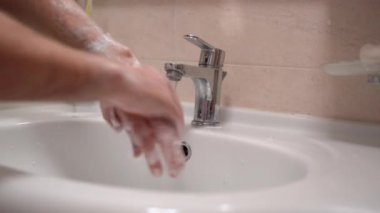 Coronavirus salgını ve enfekte insanlar, antibakteriyel sabun kullanan bir adam, sıcak su altında durulanıyor ve banyo havlusuyla kurutuluyor. Tehlikeli bulaşıcı bir dönemde hijyen kurallarına uymak