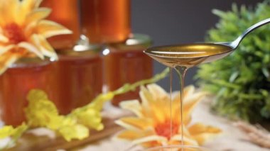 Kehribar renginde sıvı bal. Beslenme malzemeleri ve kristal kasede kaşıktan dökülen vitaminler. Çiçek üretiminde kullanılan bal kavanozlarıyla geleneksel arıcılık fuarı. Rafine edilmiş sıvı