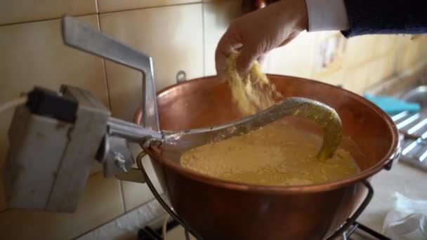 Prato tradicional de inverno italiano chamado polenta. Porriage milho cozido em fogo baixo em caldeirão de cobre, homem derramando farinha de milho em água fervente e lentamente mexendo. Cozinhar refeições de inverno em casa — Vídeo de Stock