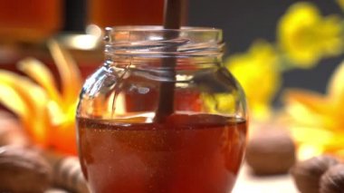 Cam kavanozda karıştırılmış bal ve çiçek arkaplanda ahşap kaplama inanılmaz bir makro atış. Saf doğal ürünün kalın kabarcık dokusu, vitaminli sağlıklı sarı ve turuncu nektar...