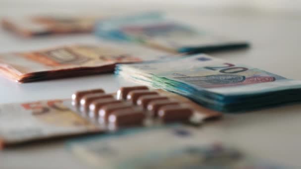 Spadające kapsułki medyczne pakowane na stosy banknotów euro, drogie leczenie medyczne. Opieka zdrowotna wysokie koszty leczenia, korzyści ekonomiczne. Papierowa waluta i medycyna — Wideo stockowe