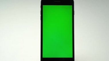 Dikey yeşil ekranlı cep telefonunun arka planına para dökülüyor. Finansal ticari işlemler için para kazanmak, farklı harcamalar için kağıt para biriktirmek veya gayrimenkul satın almak