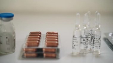 Eczane fabrikası, tablet, kapsül, ilaç ve aşı şişelerinin üretimi hastane laboratuarındaki masanın üzerinde. İlaç üretimi, uyuşturucu üretimi, eczane