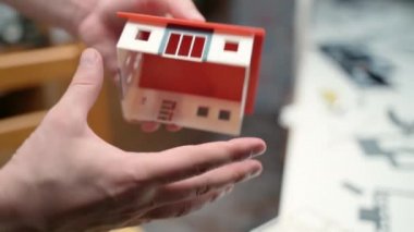 Erkek mühendis, masion modelinin yapımı için plastik ve kağıt tasarımcısı ürünleri, müşteriler için emlak modeli kullanıyor. Emlak inşaat projesi, minyatür evler. Mühendislik