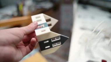 Profesyonel bir mimar işyerinde ev modelleri yapıyor. Ev duvarları, pencereler, kapılar ve çatı yapımında renkli plastik parçaları kullanan bir adam. Tasarımcı minyatür ev geliştiriyor