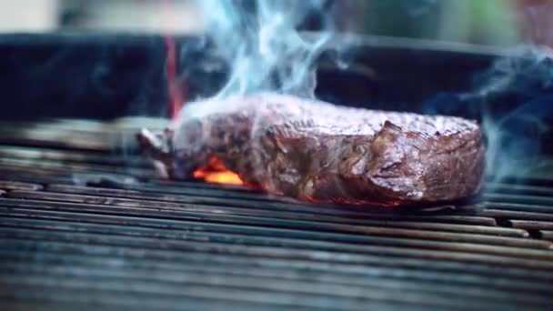 Roasting juicy aged primed rare meat steak in slow motion, grilled beef steak on barbecue grid, fiery meat grilling with burning flames and smoke. Preparation of barbecue in brazier grill in open — Stock Video