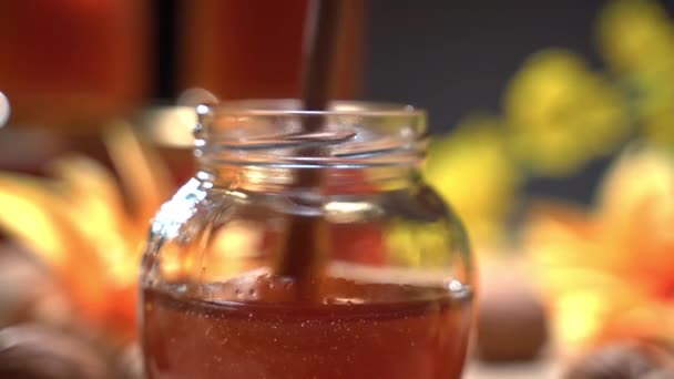 Texture de bulles épaisses de miel doré pur naturel dans un bocal en verre, en remuant le produit naturel avec une cuillère en bois et en créant des bulles à l'intérieur. Ingrédient naturel pour la thérapie alternative, les aliments et les boissons — Video