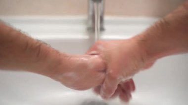 Bulaşıcı virüs enfeksiyonu kavramı, adamın ellerini antibakteriyel sabunla dikkatlice yıkaması, parmaklarını ovuşturması ve sıcak suyun altında durulaması. Kovid19 'u önlemek için alkol dezenfektan jeli kullanılıyor.