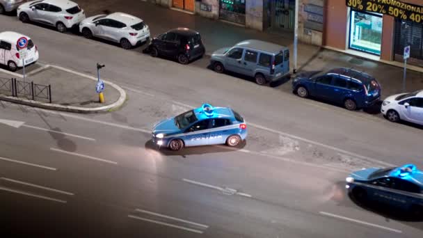 ŘÍM, ITÁLIE - 20. března 2020: Noční hlídkové vozy přijíždějí v noci na křižovatku Říma za účelem dalšího sledování dopravy, dvě modrá policejní auta s blikající sirénou na střeše, policejní kontrola zapnutá — Stock video
