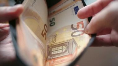 Siyah deri cüzdandan euro banknotlarını sayan bir işadamı, ipotek ödemeleri ve masraflar için para biriktiren bir iş adamı. Para harcamaları ve mali kriz, para birimi ve işsizlik