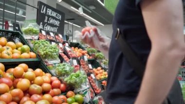 NAPLES, İtalya - 18 Mayıs 2020: Covid-19 salgını sırasında Napoli, süpermarkette kamu mesafesini takip eden müşteri, raflarda taze domatesleri seçen adam.